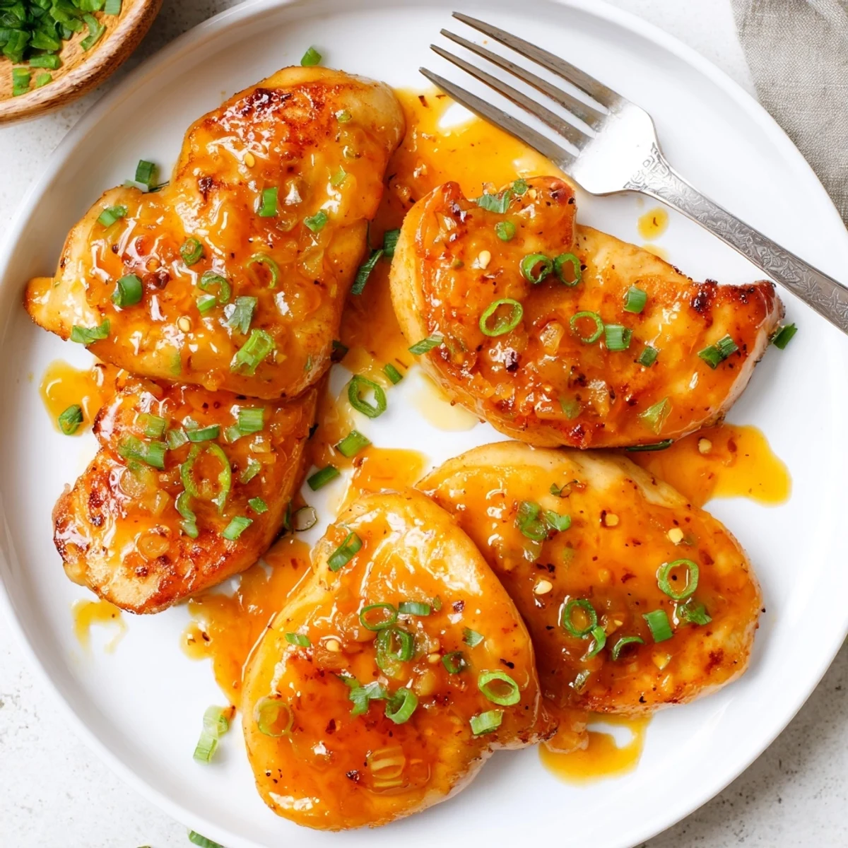 Bubbling apricot sauce coating tender seared chicken pieces in a white oven-safe skillet