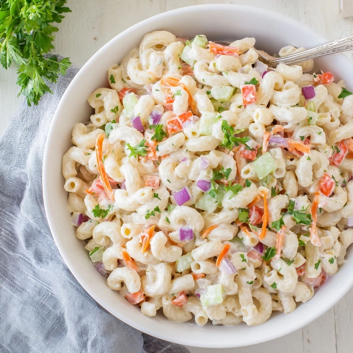 Creamy homemade macaroni salad with colorful diced vegetables in a white serving bowl