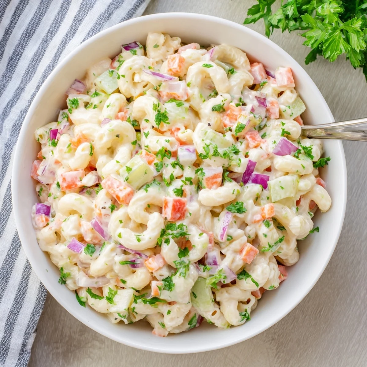 Classic American macaroni salad coated in rich dressing with fresh parsley garnish on top