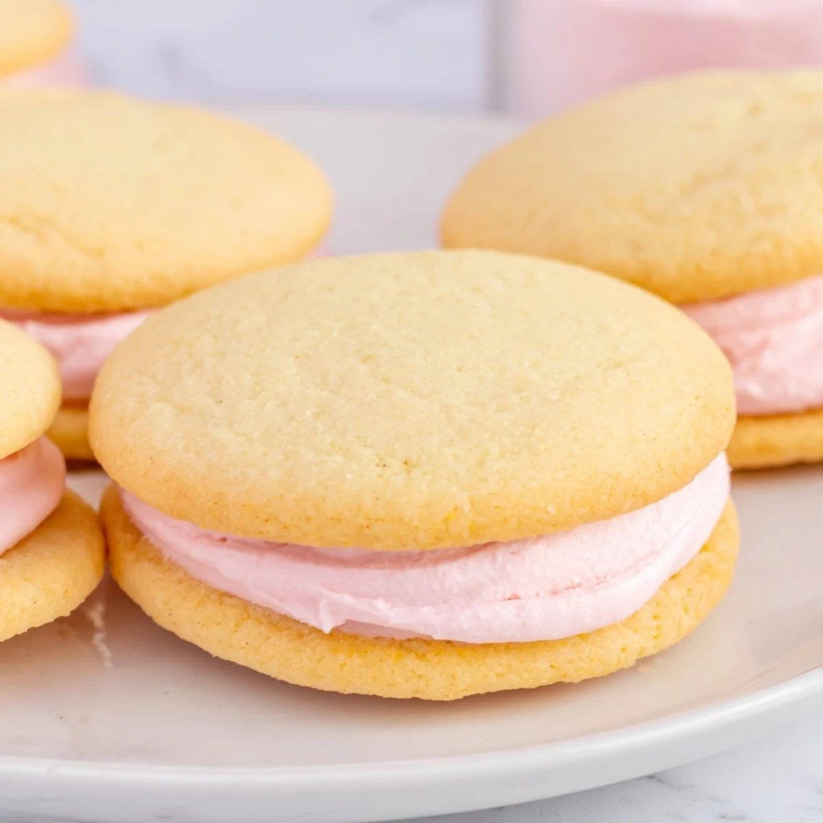Soft Pastel Sugar Cookie Sandwiches arranged on a rustic wooden cutting board with sprinkles