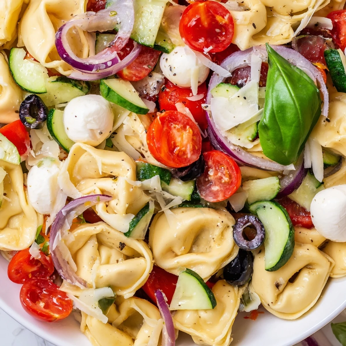 Colorful tortellini salad with cherry tomatoes, cucumber, and mozzarella tossed in zesty Italian dressing