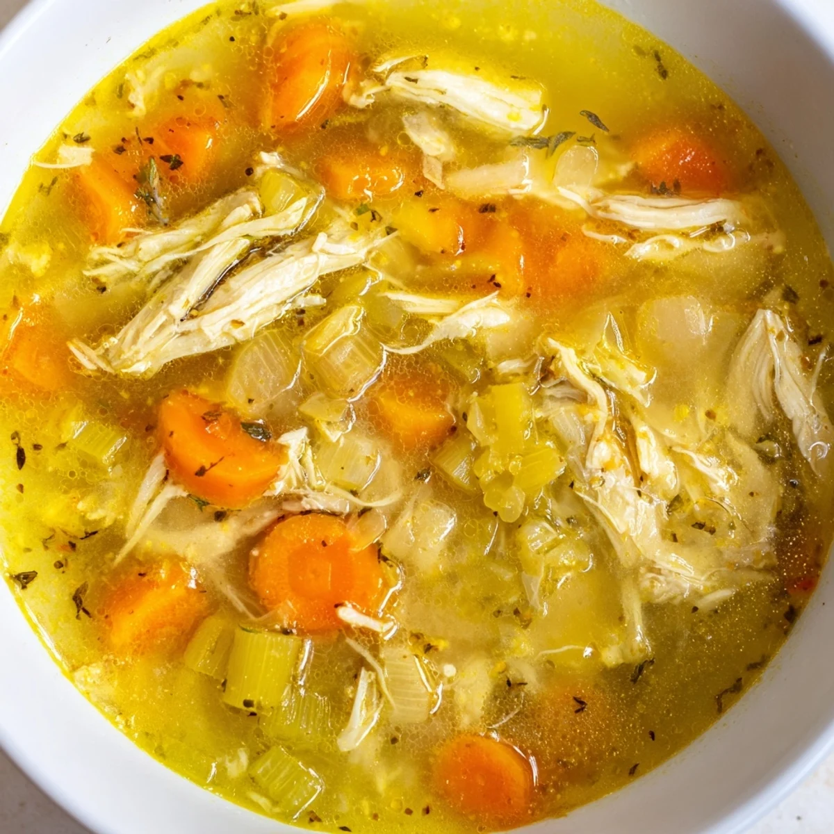 Golden Crockpot Lemon Chicken Soup loaded with carrots, celery, and fresh parsley garnish