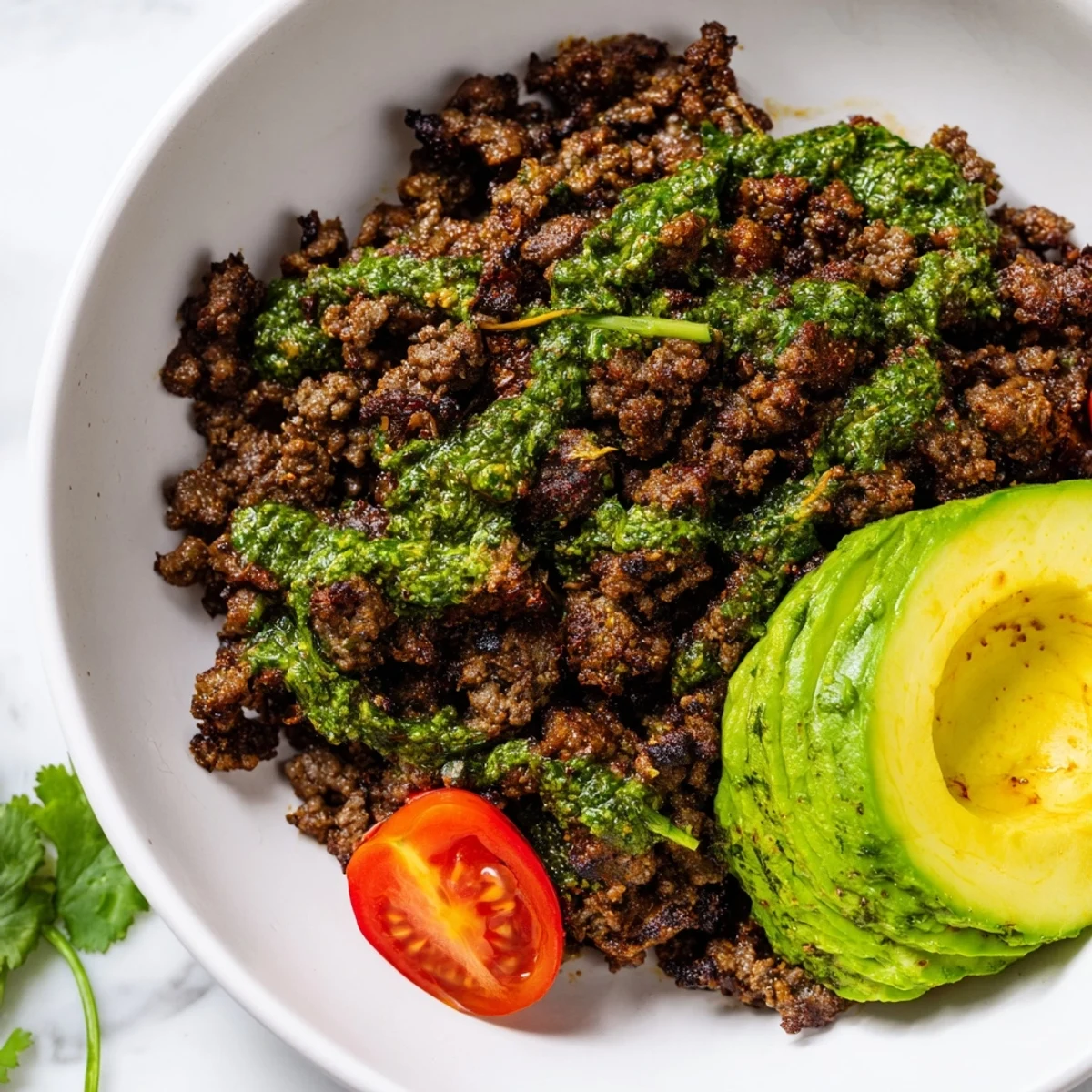 Seasoned chimichurri ground beef bowls topped with fresh avocado slices and colorful crisp vegetables