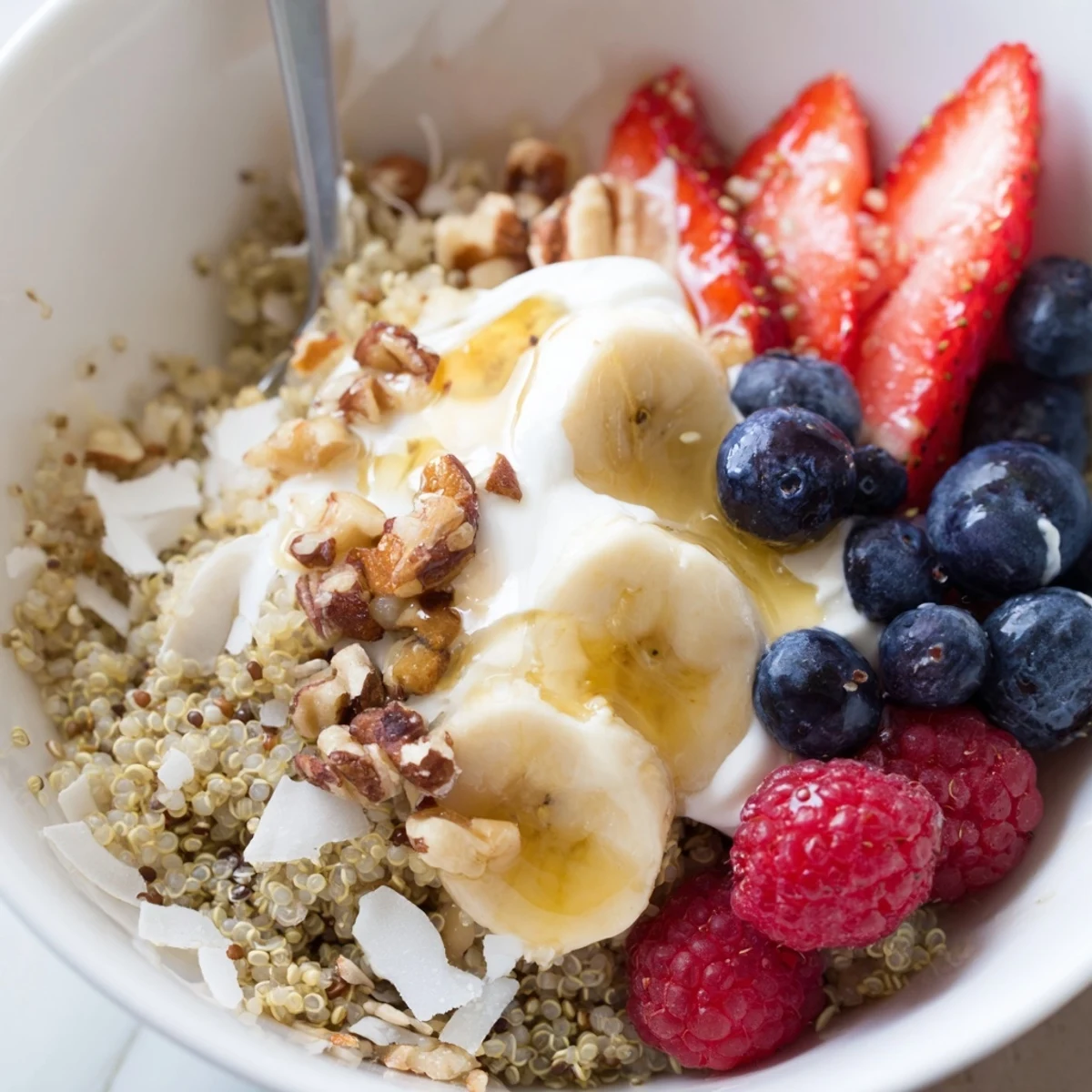 Warm Quinoa Breakfast Bowl topped with creamy yogurt, honey, fresh berries