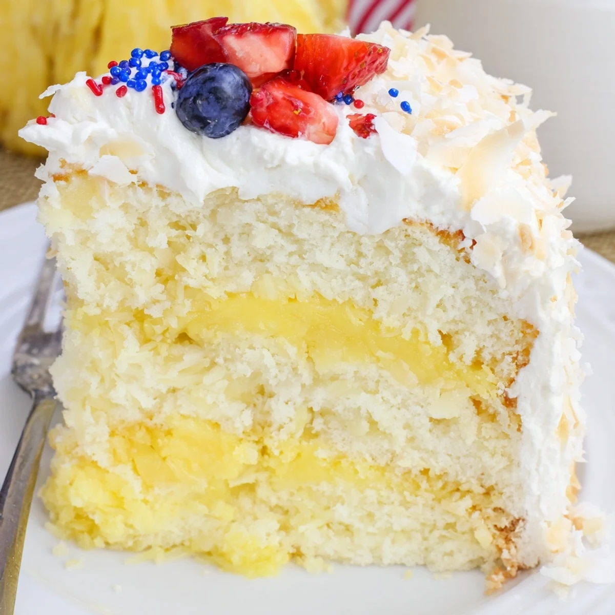 Close-up of patriotic Pineapple Coconut God Bless America Cake slice, juicy pineapple filling