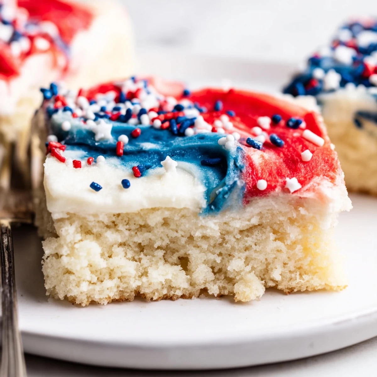 Patriotic Sugar Cookie Bars topped with swirled red, white, and blue frosting.  