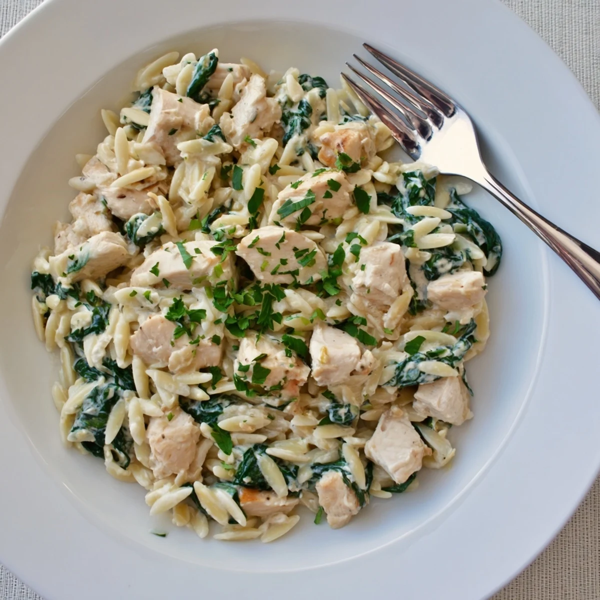 Savory chicken and orzo cooked in garlic Boursin sauce with vibrant green spinach