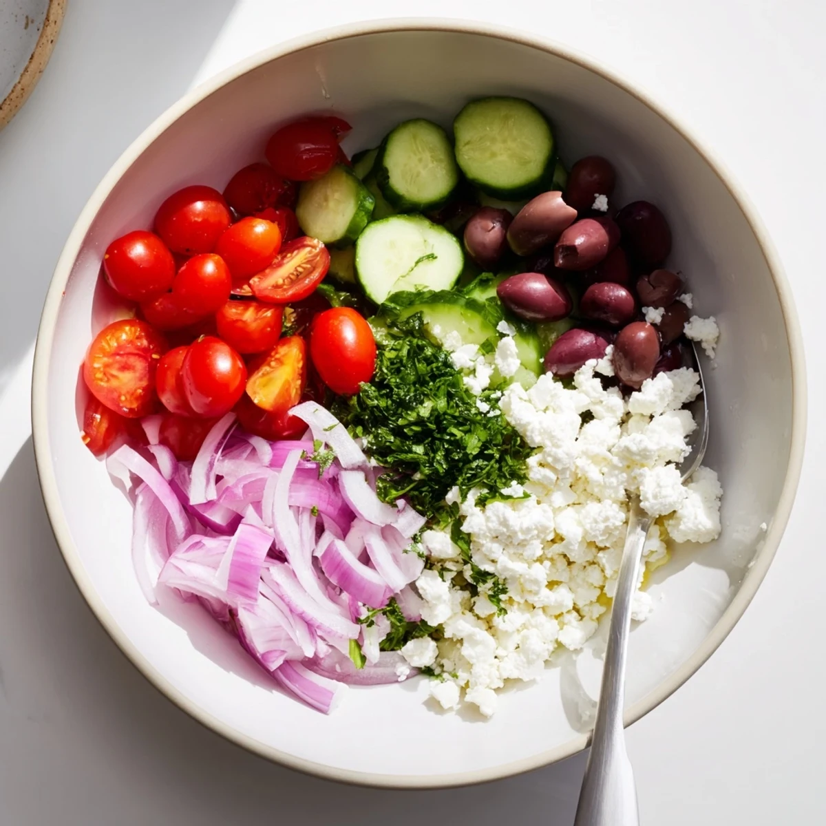 Creamy Greek salad cottage cheese bowl topped with fresh vegetables, olives, and crumbled feta