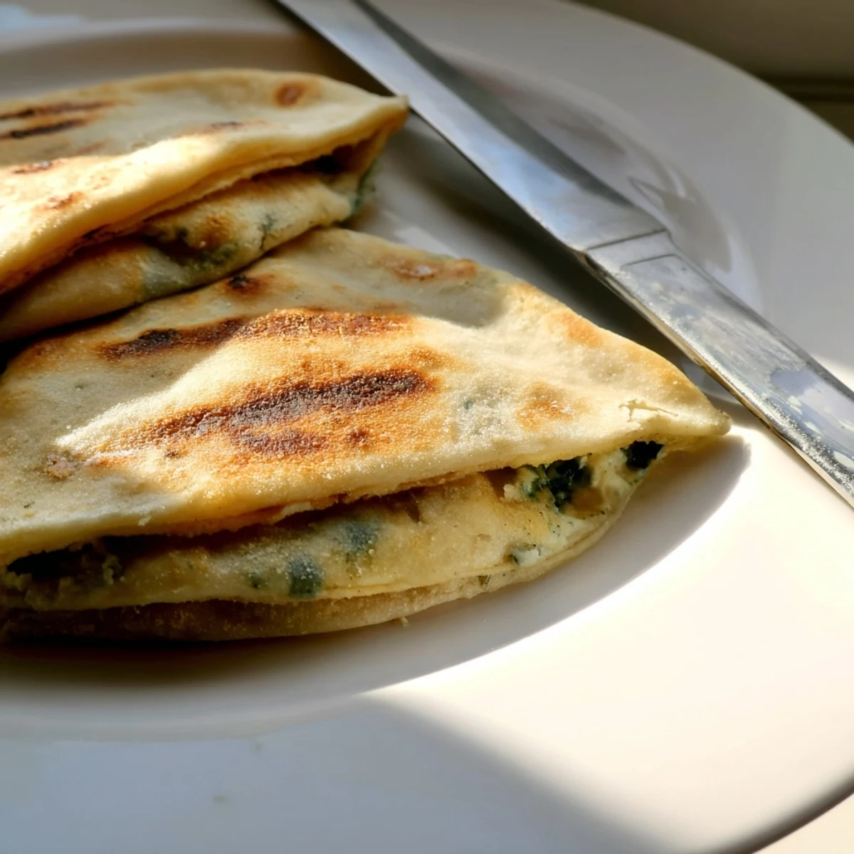 Crispy pan-fried Turkish Gozleme flatbread featuring spinach and feta cheese filling on wooden board