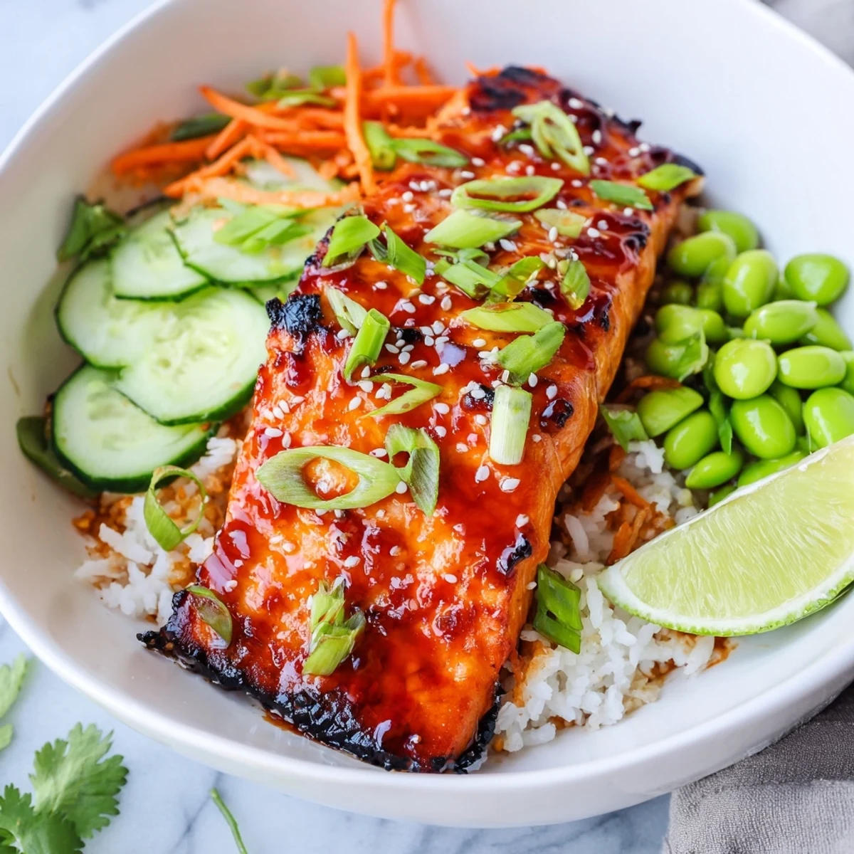 Glossy sriracha honey glazed salmon fillets rest on steamed rice with crisp vegetables.