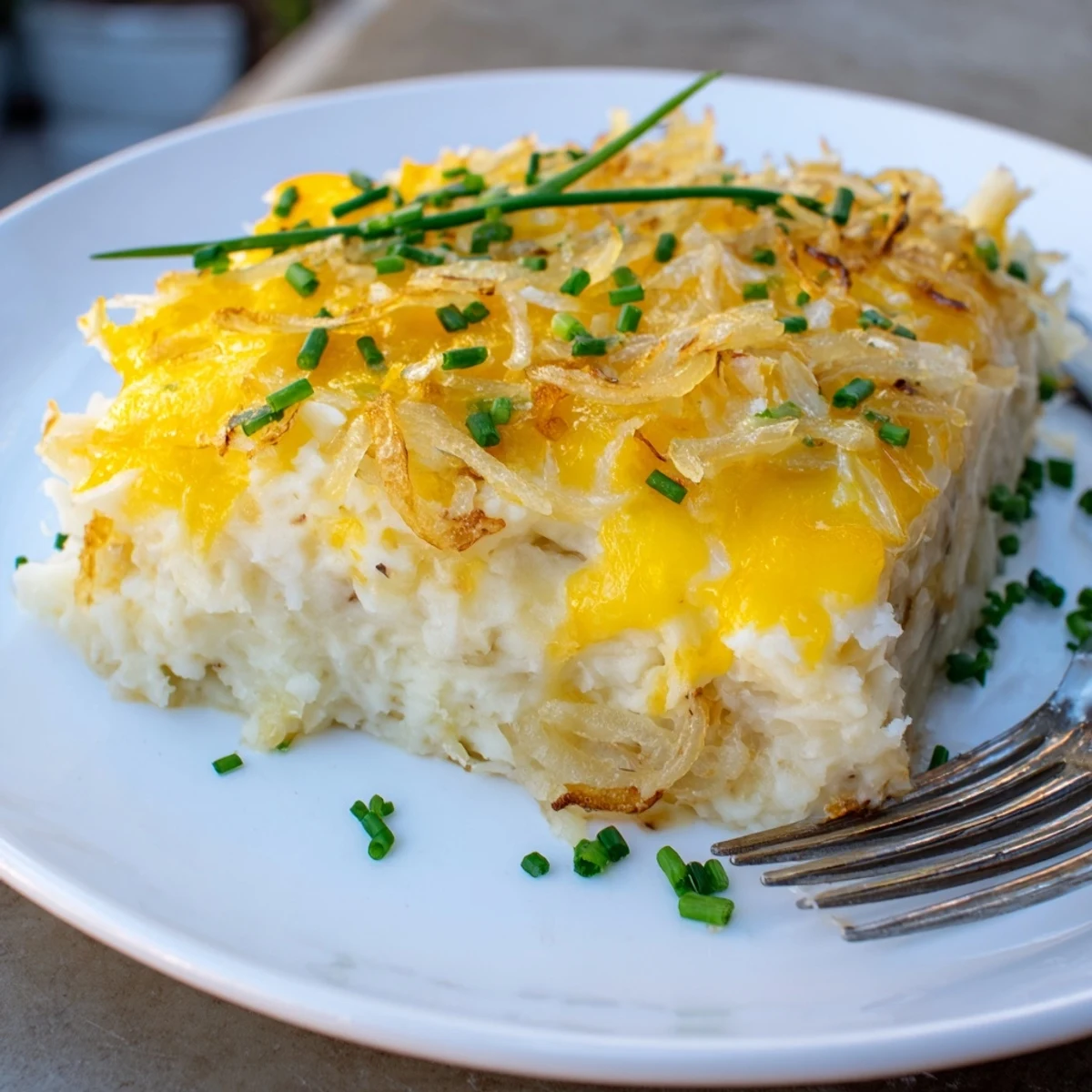 Golden baked Cheesy Onion Mashed Potato Casserole topped with melted cheddar and fresh chives