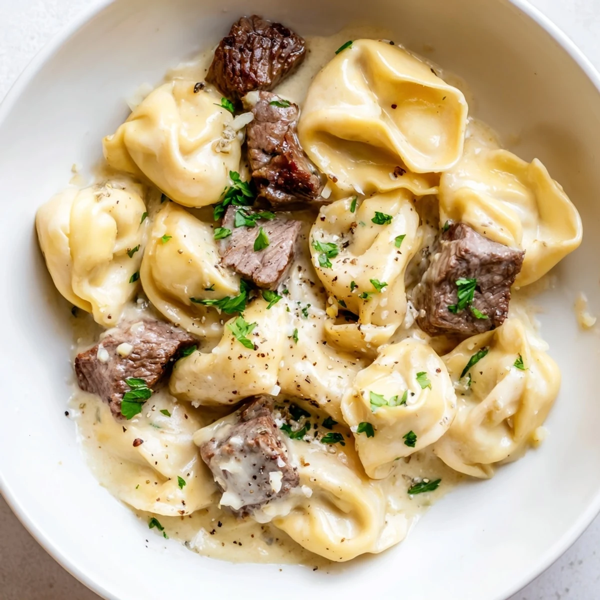 Creamy garlic steak tortellini served in a golden parmesan sauce with fresh parsley