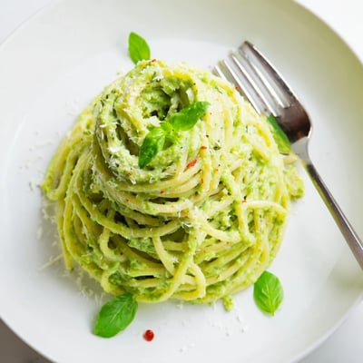 Vibrant green herbaceous Green Goddess Pasta Sauce drizzled over steaming penne in a bowl